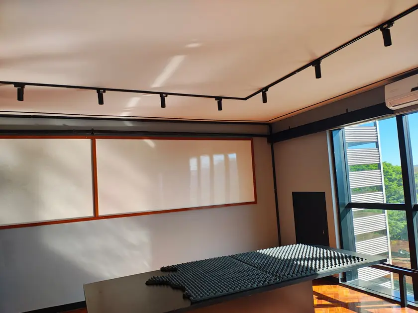 Escritório com trilhos de luz, persiana e mesa de reunião