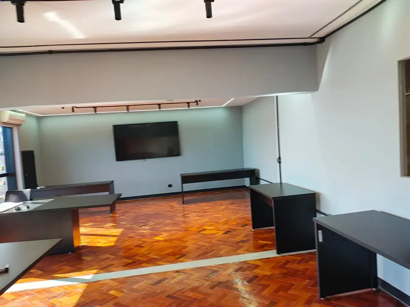 Sala corporativa com piso em taco e painel de TV