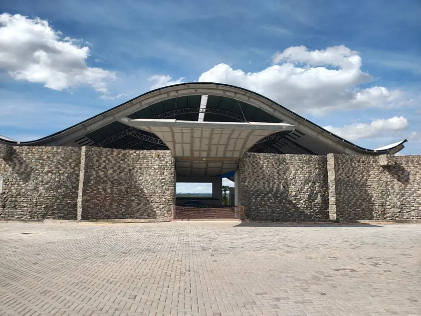 Obra institucional com cobertura curva e paredes em pedra
