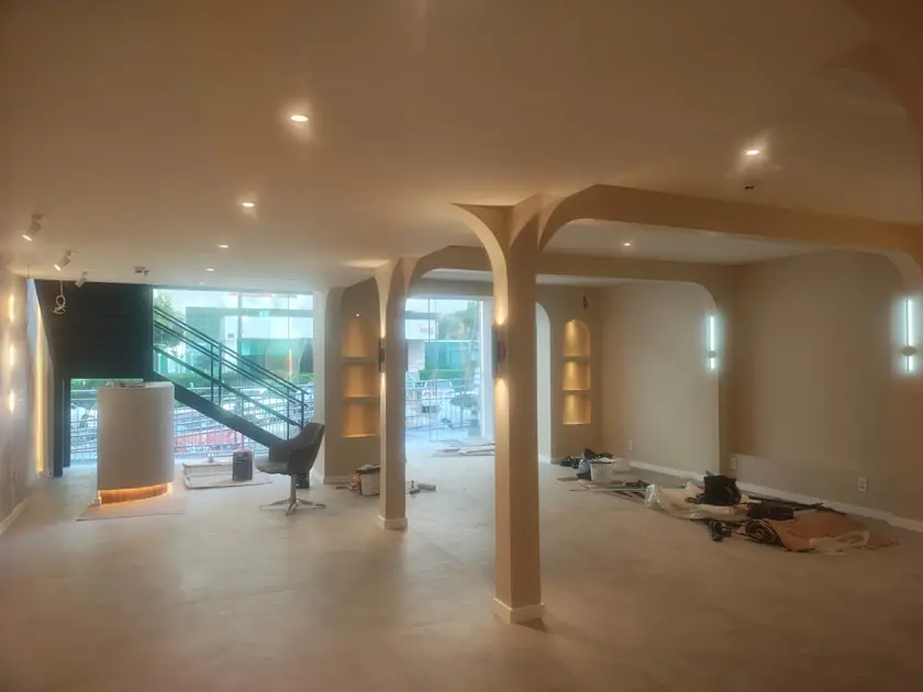 Loja comercial com arcos em gesso, nichos iluminados e escada metálica